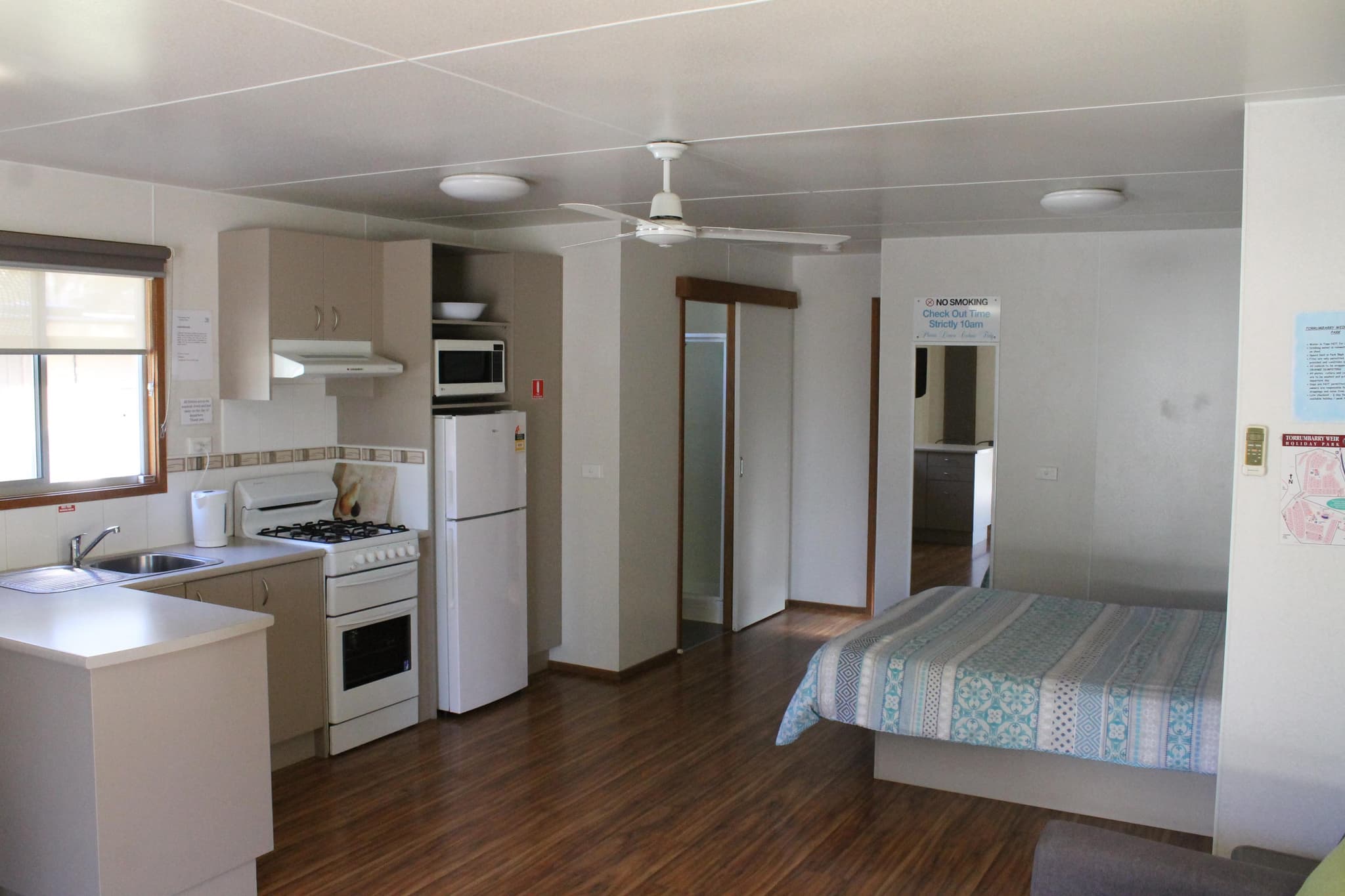 Fleetwood Rainbow Cabin open-plan kitchen and bedroom at Torrumbarry Weir Holiday Park, Patho, with full kitchen, ceiling fan and queen bed