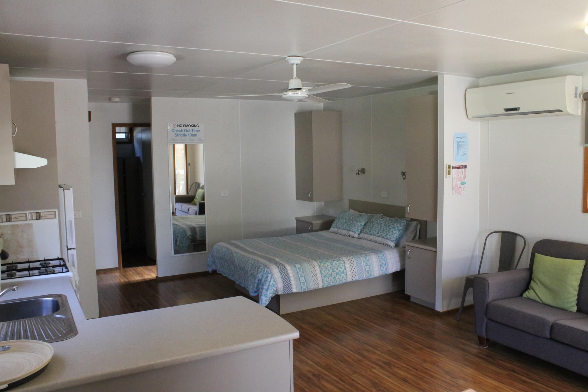 Open-plan cabin interior with queen bed, kitchenette and lounge at Torrumbarry Weir Holiday Park, Patho VIC