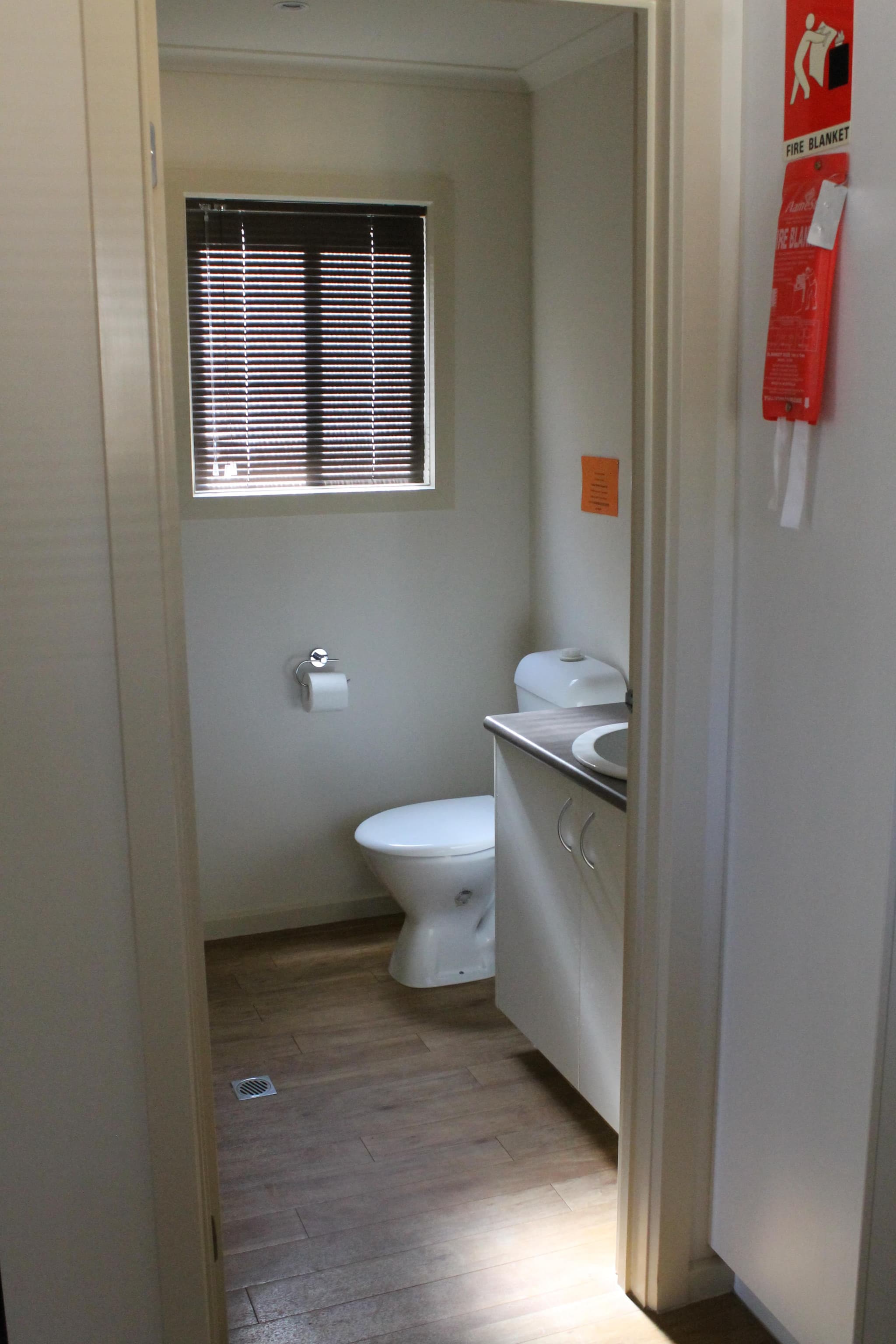 Bathroom in the Southern Cross Cabin at Torrumbarry Weir Holiday Park, with toilet, vanity sink and timber-look flooring