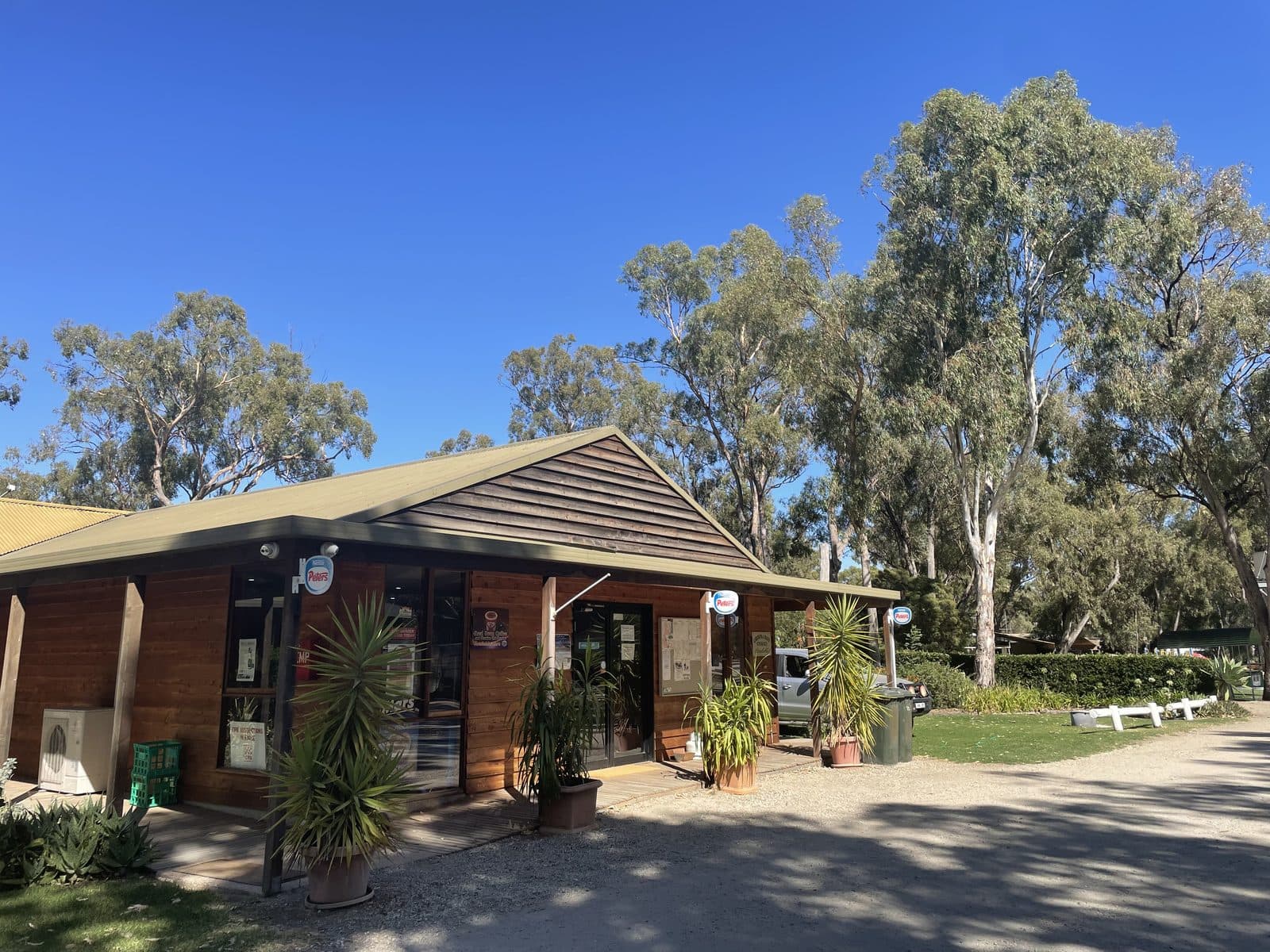 Timber office and reception building at Torrumbarry Weir Holiday Park, Patho VIC, with gum trees and gravel driveway